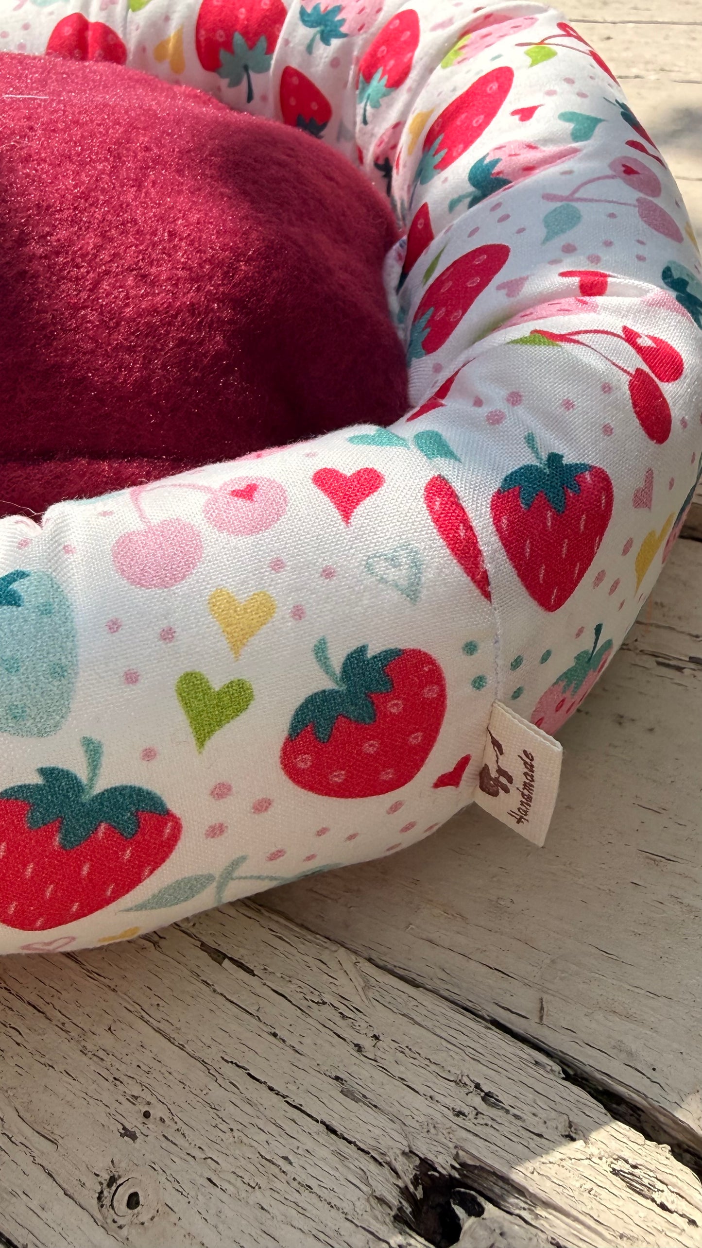 Handgefertigter Kuscheldonut für Meerschweinchen, weiches Kleintierbett mit fröhlichem Erdbeer-, Kirsch- und Herzchen-Muster auf weißem Grund, gemütlicher Rückzugsort aus Dein Krämerladen.