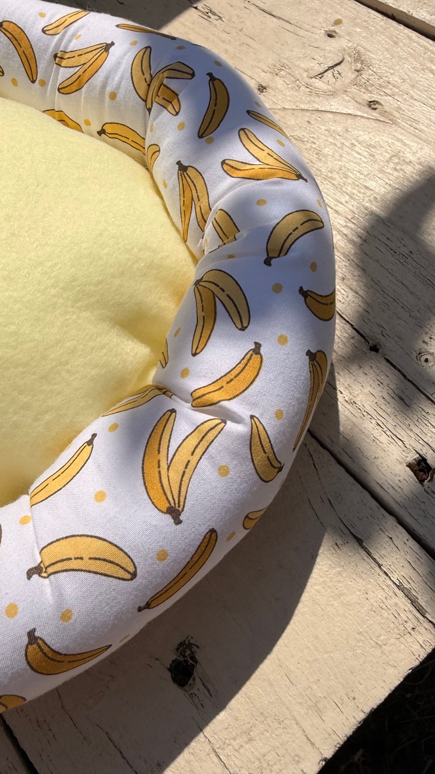 Handgefertigter Kuscheldonut für Meerschweinchen, heller Stoff mit gelbem Bananen-Muster und Punkten, weiches und gemütliches Kleintierbett aus Dein Krämerladen.
