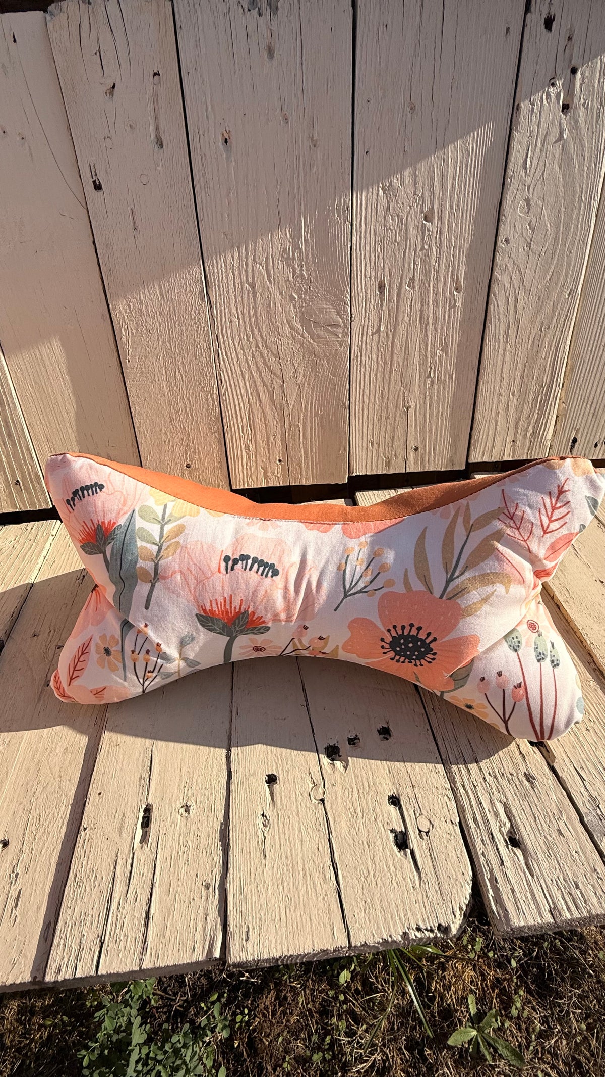 Handgefertigter Leseknochen als Nackenkissen, heller Stoff mit zarten peach- und korallfarbenen Blumen und Blättern, kombiniert mit einfarbig terracottafarbenem Stoff, aus Dein Krämerladen.