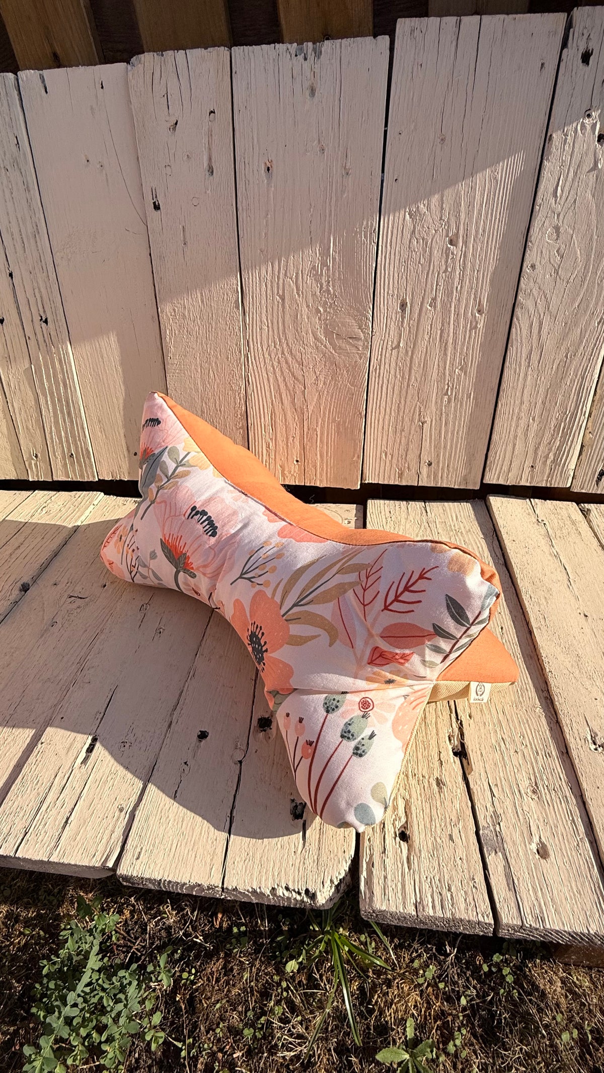 Handgefertigter Leseknochen als Nackenkissen, heller Stoff mit zarten peach- und korallfarbenen Blumen und Blättern, kombiniert mit einfarbig terracottafarbenem Stoff, aus Dein Krämerladen.