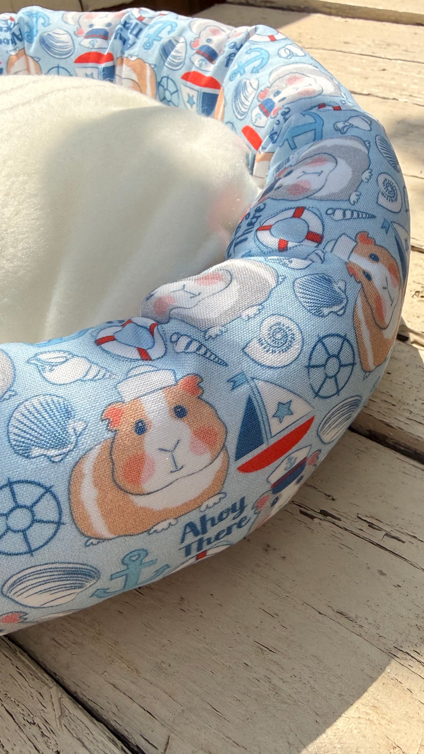 Handgefertigter Kuscheldonut für Meerschweinchen, hellblauer Stoff mit niedlichem Meerschweinchen-Matrosen-Motiv, Segelbooten und Ankern, gemütliches Kleintierbett aus Dein Krämerladen.