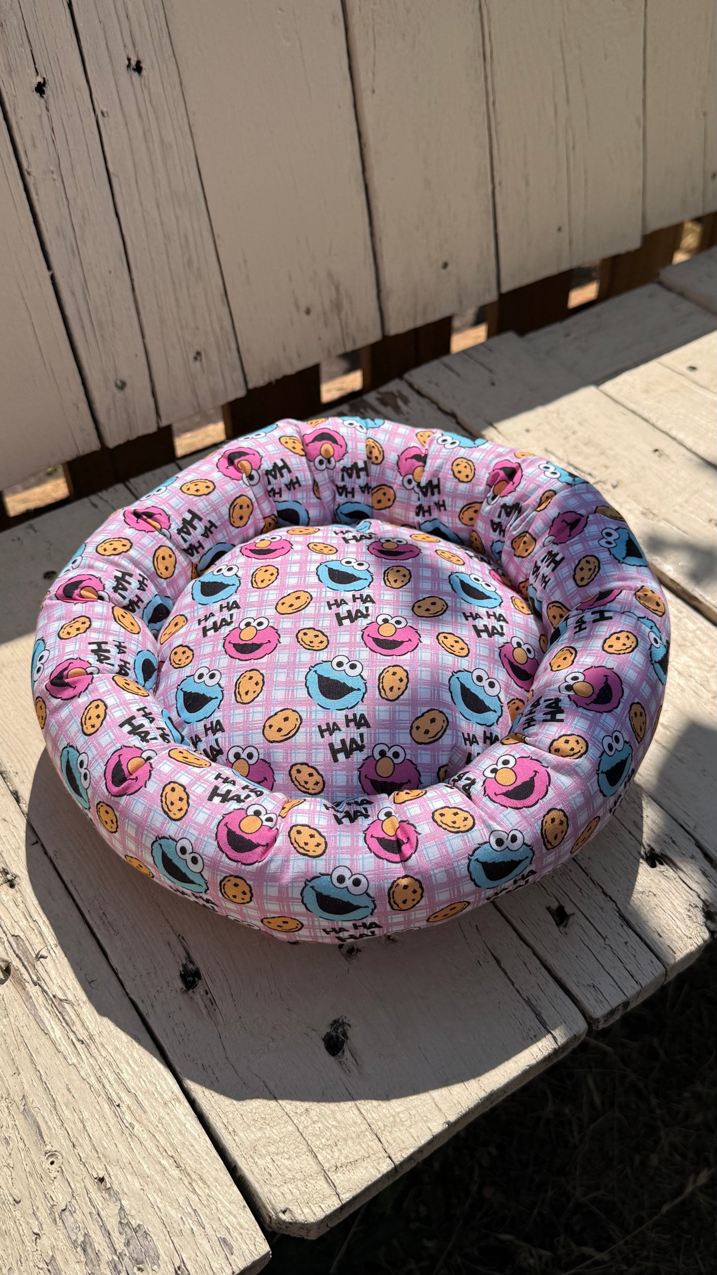 Handgefertigter Kuscheldonut für Meerschweinchen und Kleintiere, rosa karierter Stoff mit Krümelmonster- und Elmo-Motiven sowie "HA HA HA!"-Schriftzug, weiches Kleintierbett aus Dein Krämerladen