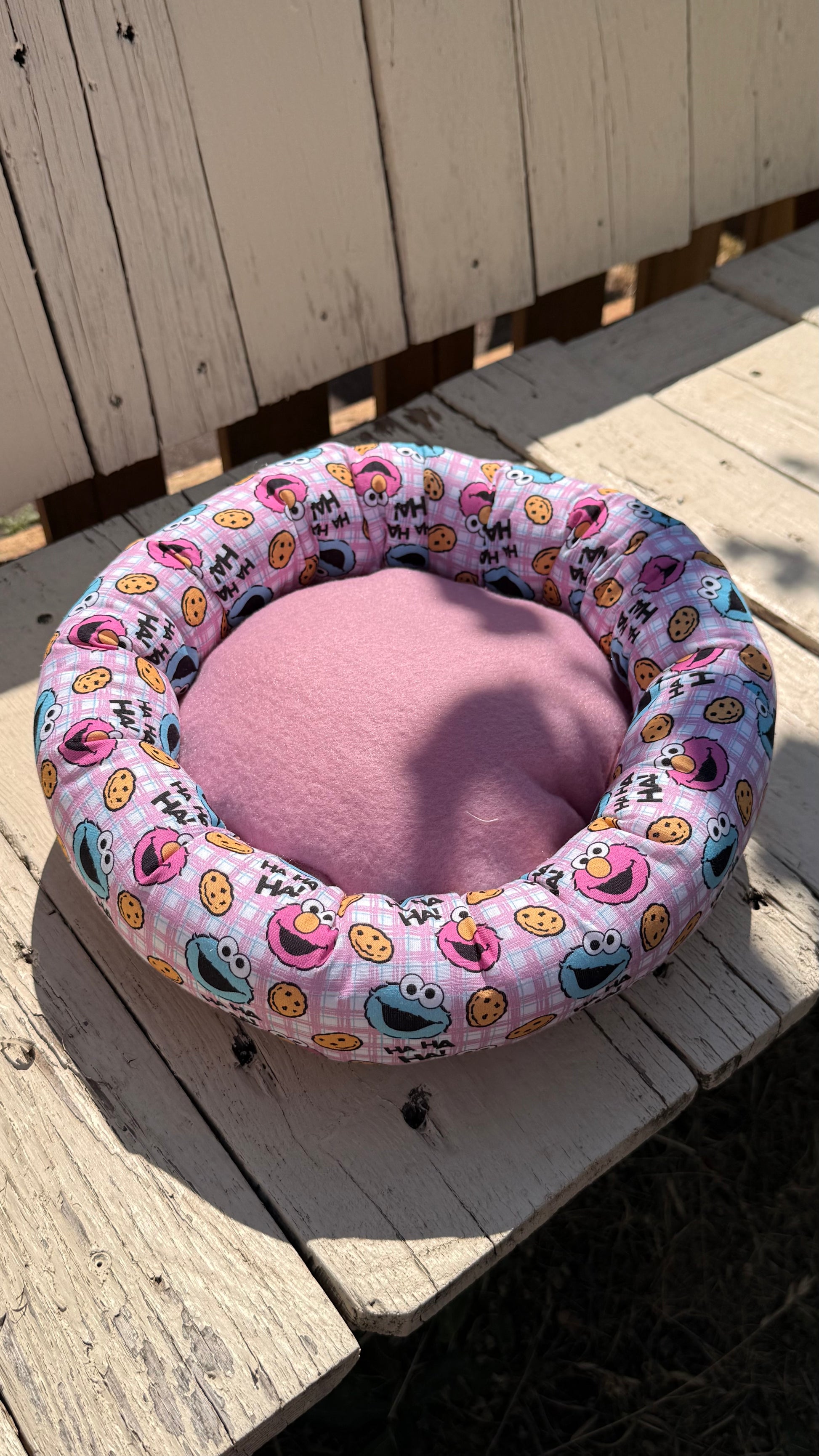 Handgefertigter Kuscheldonut für Meerschweinchen und Kleintiere, rosa karierter Stoff mit Krümelmonster- und Elmo-Motiven sowie "HA HA HA!"-Schriftzug, weiches Kleintierbett aus Dein Krämerladen