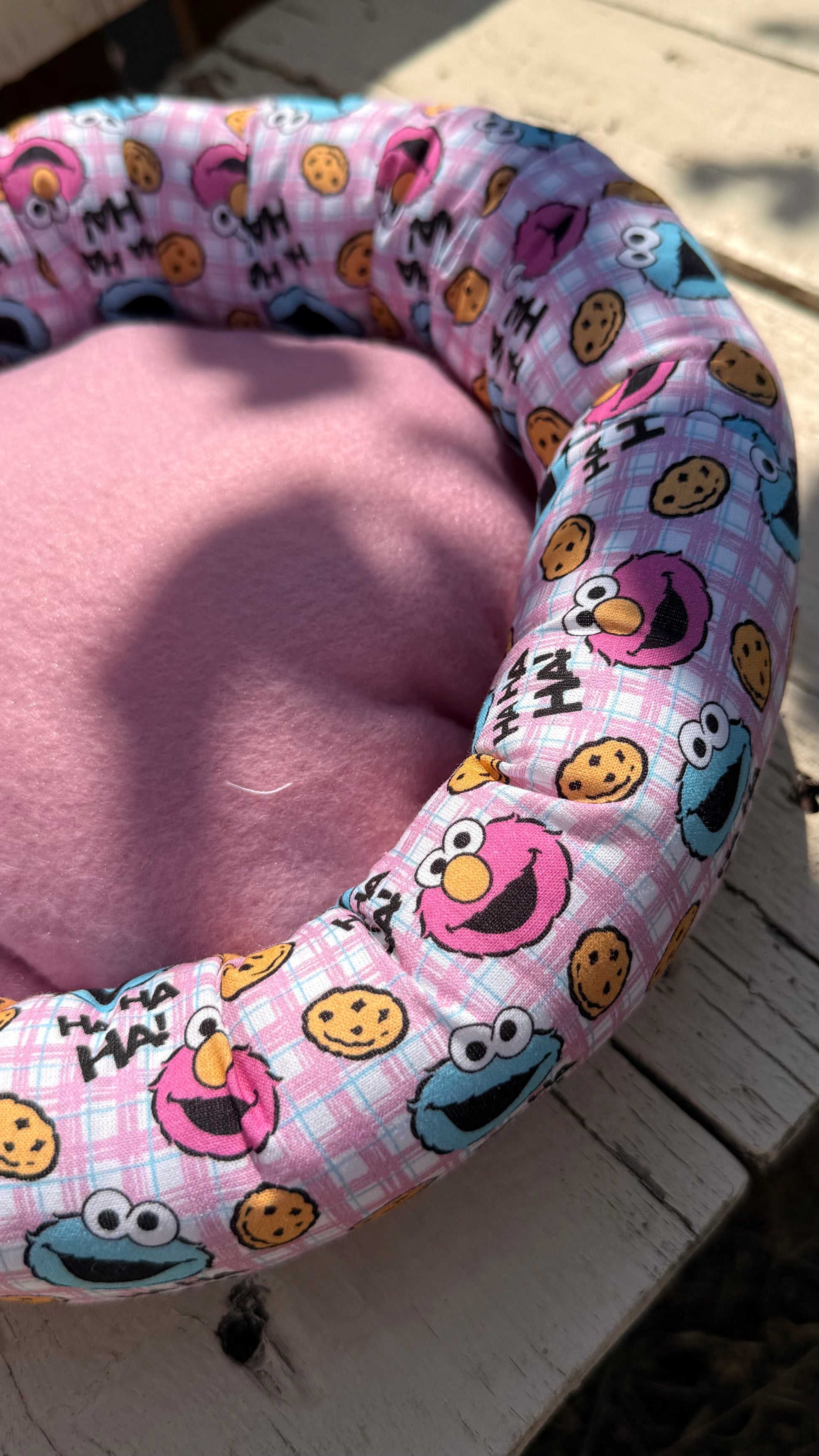 Handgefertigter Kuscheldonut für Meerschweinchen und Kleintiere, rosa karierter Stoff mit Krümelmonster- und Elmo-Motiven sowie "HA HA HA!"-Schriftzug, weiches Kleintierbett aus Dein Krämerladen