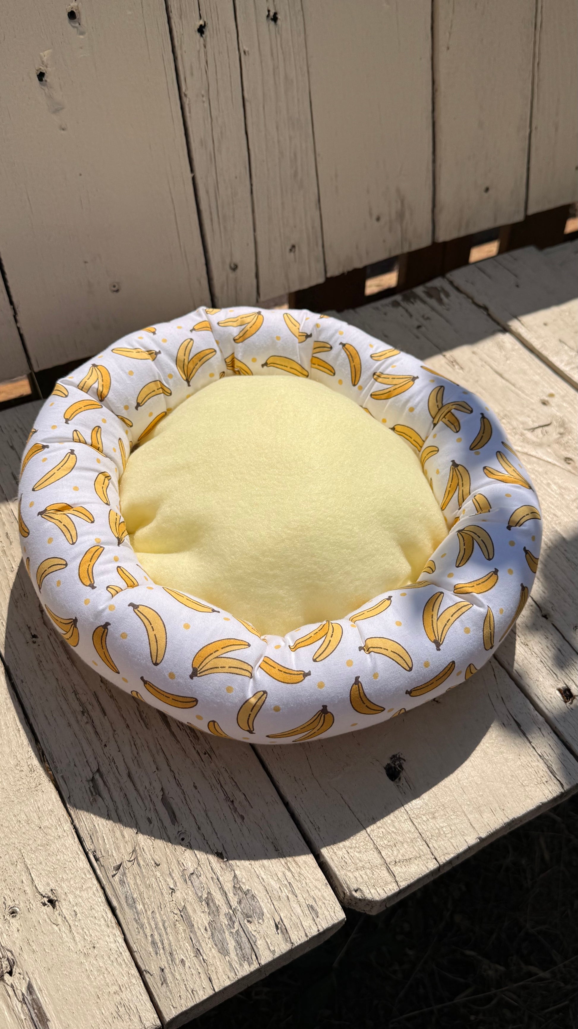 Handgefertigter Kuscheldonut für Meerschweinchen, heller Stoff mit gelbem Bananen-Muster und Punkten, weiches und gemütliches Kleintierbett aus Dein Krämerladen.