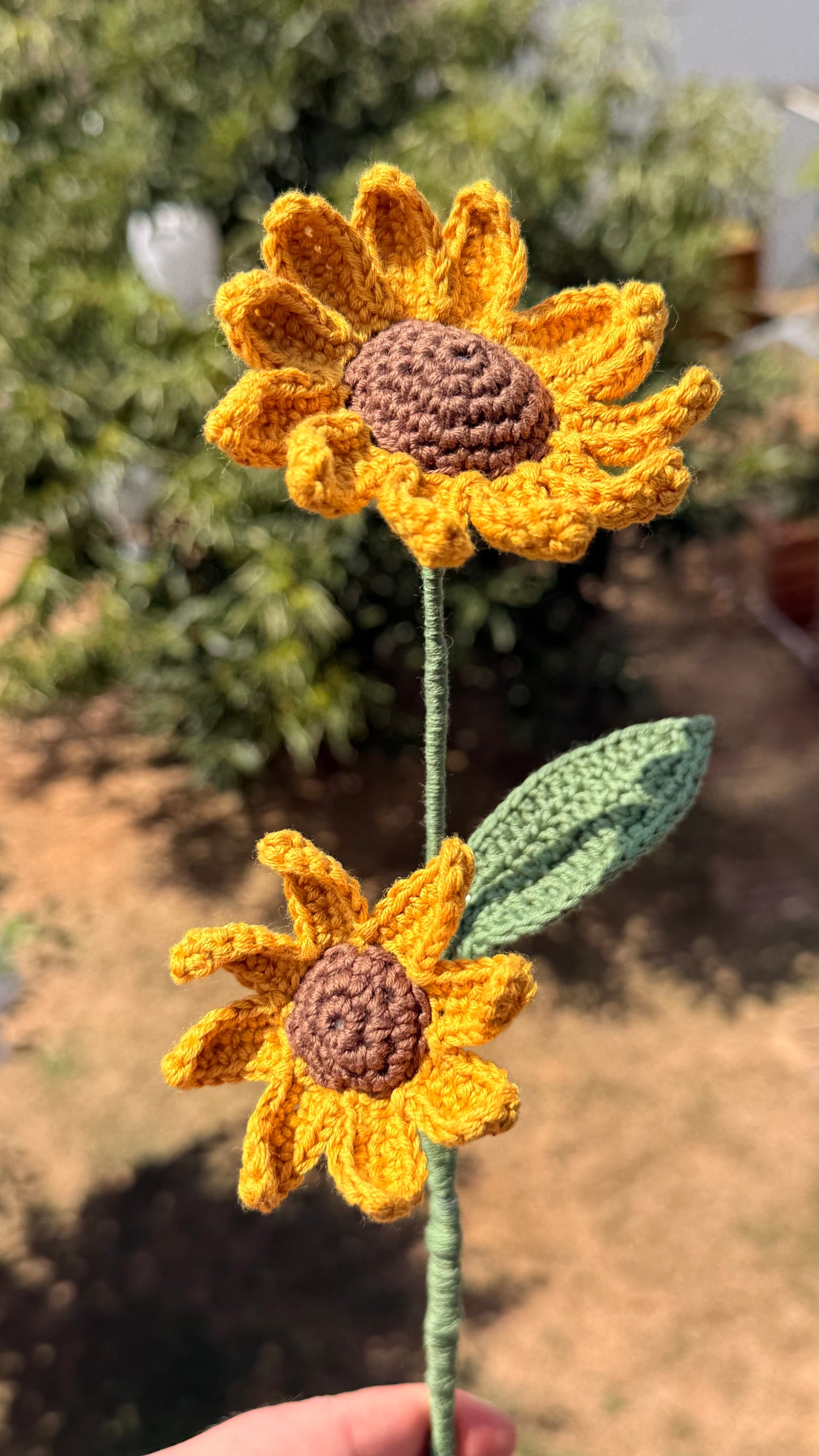 Handgehäkelte Sonnenblume mit zwei gelben Blütenköpfen, brauner Mitte, grünem Stiel und Blatt, handgemachte Häkelblume aus Dein Krämerladen