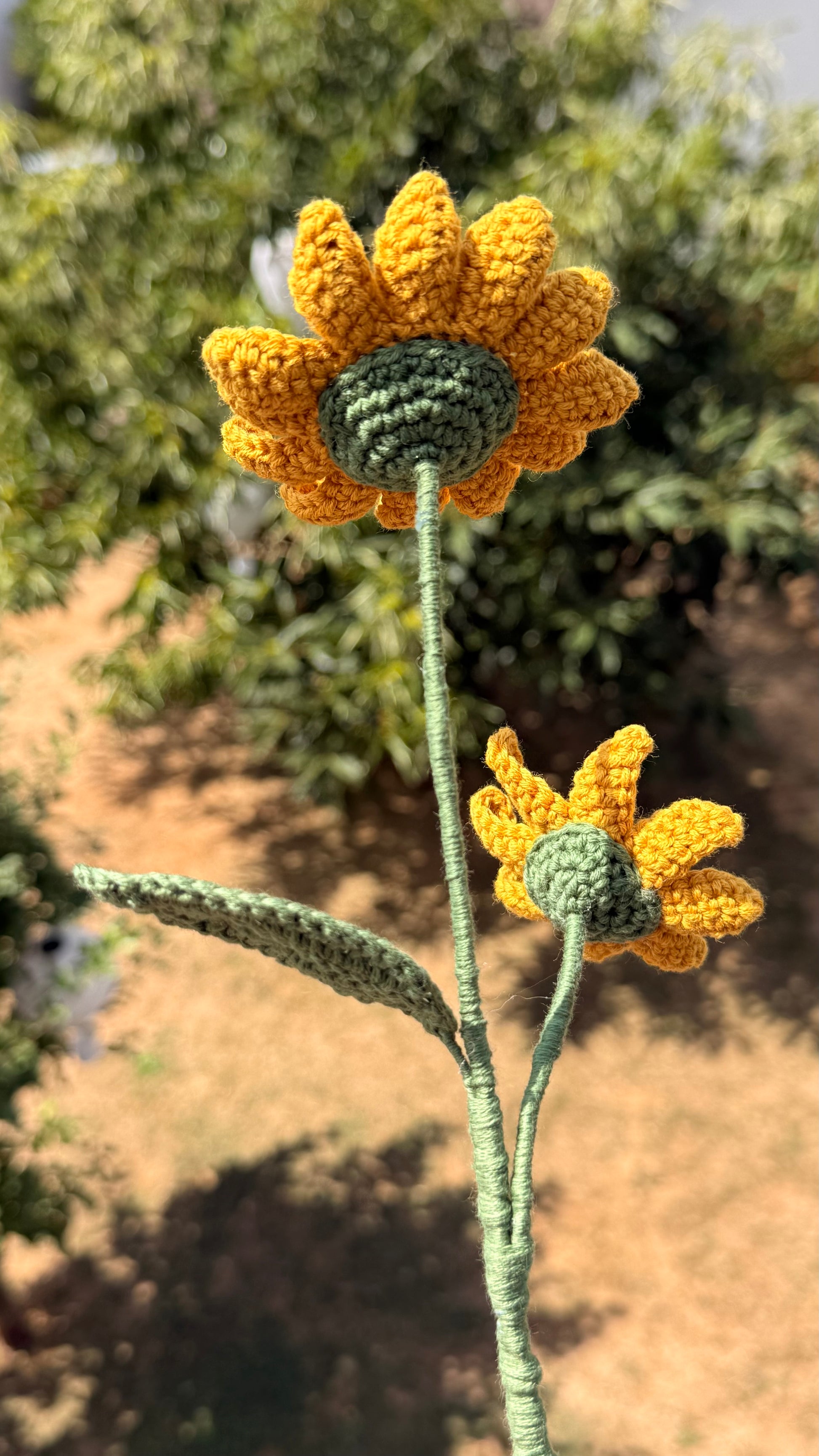 Handgehäkelte Sonnenblume mit zwei gelben Blütenköpfen, brauner Mitte, grünem Stiel und Blatt, handgemachte Häkelblume aus Dein Krämerladen
