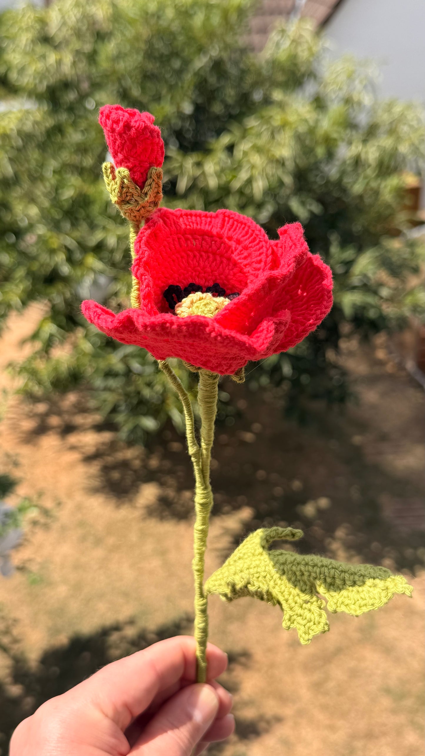 Handgehäkelte rote Mohnblume mit offener Blüte, einer geschlossenen Knospe und grünem Stiel mit Blättern, handgemachte Häkelblume aus Dein Krämerladen.