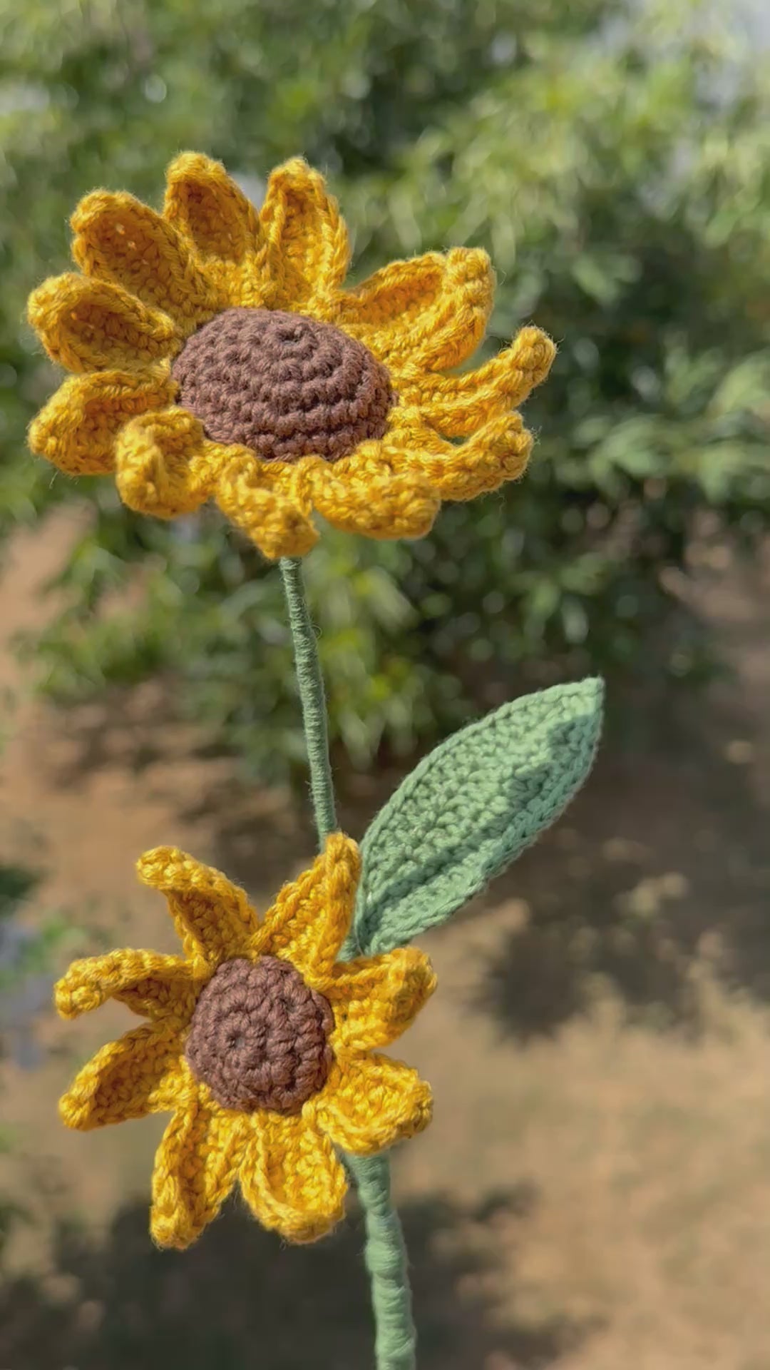 Handgehäkelte Sonnenblume mit zwei gelben Blütenköpfen, brauner Mitte, grünem Stiel und Blatt, handgemachte Häkelblume aus Dein Krämerladen